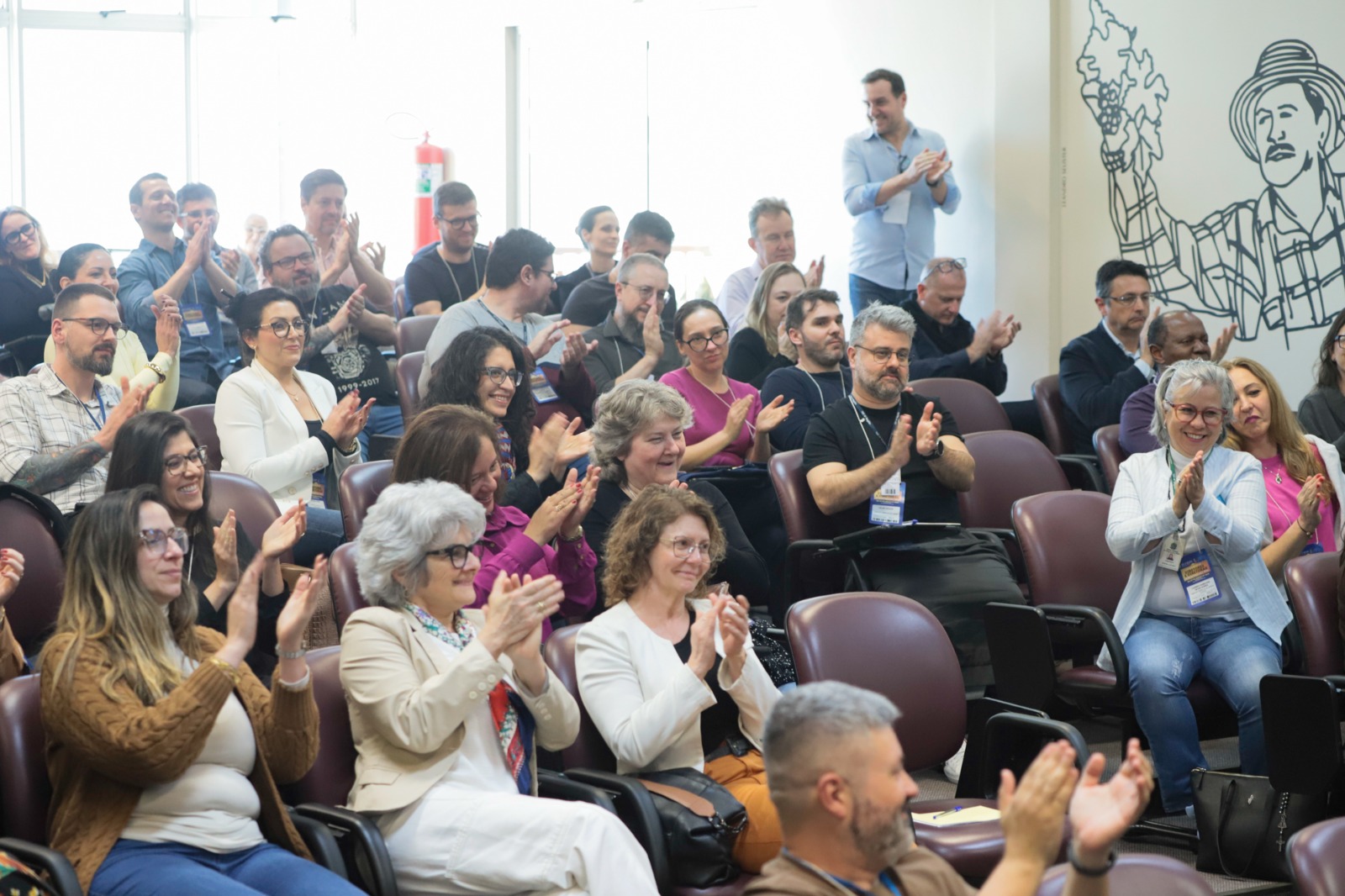Diversas pessoas na plateia aplaudindo.