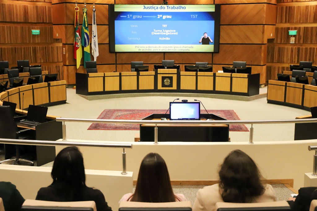 Estudantes assistem a vídeo institucional no plenário.