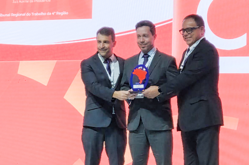 Geraldo, Rodrigo e André, segurando o troféu, no palco do evento.