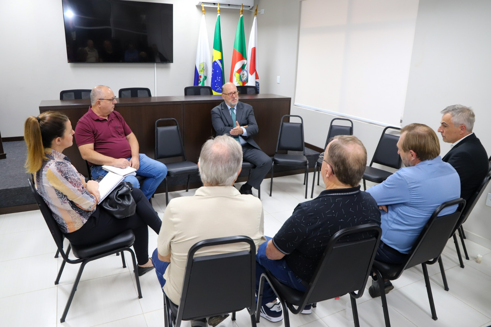 A foto mostra reunião numa roda. Todos sentados.