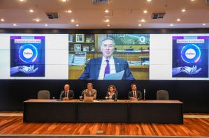 A foto mostra uma mesa de autoridades e o presidente Barroso de fundo, num telão.