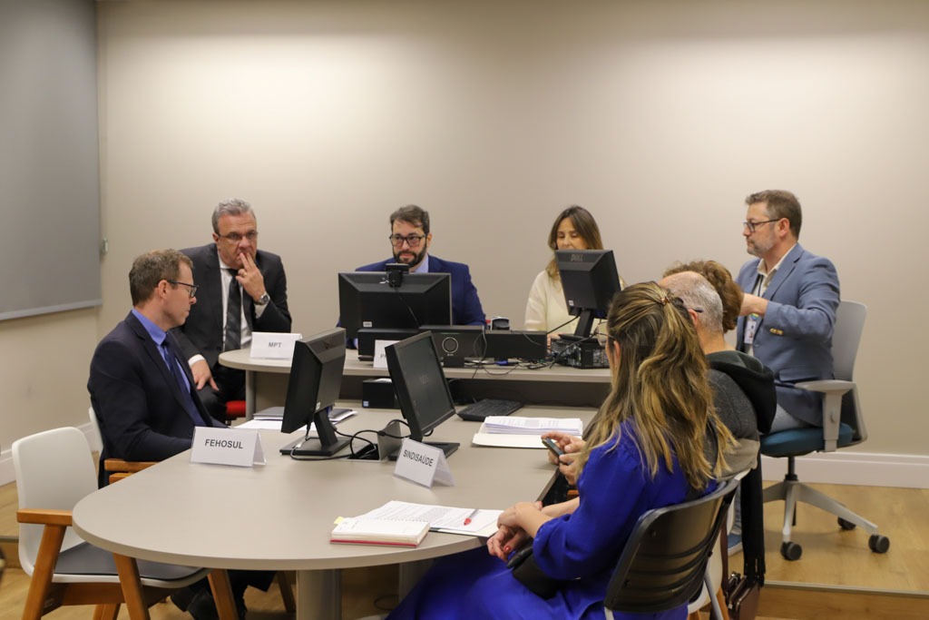 A foto mostra a mesa de audiência com os participantes