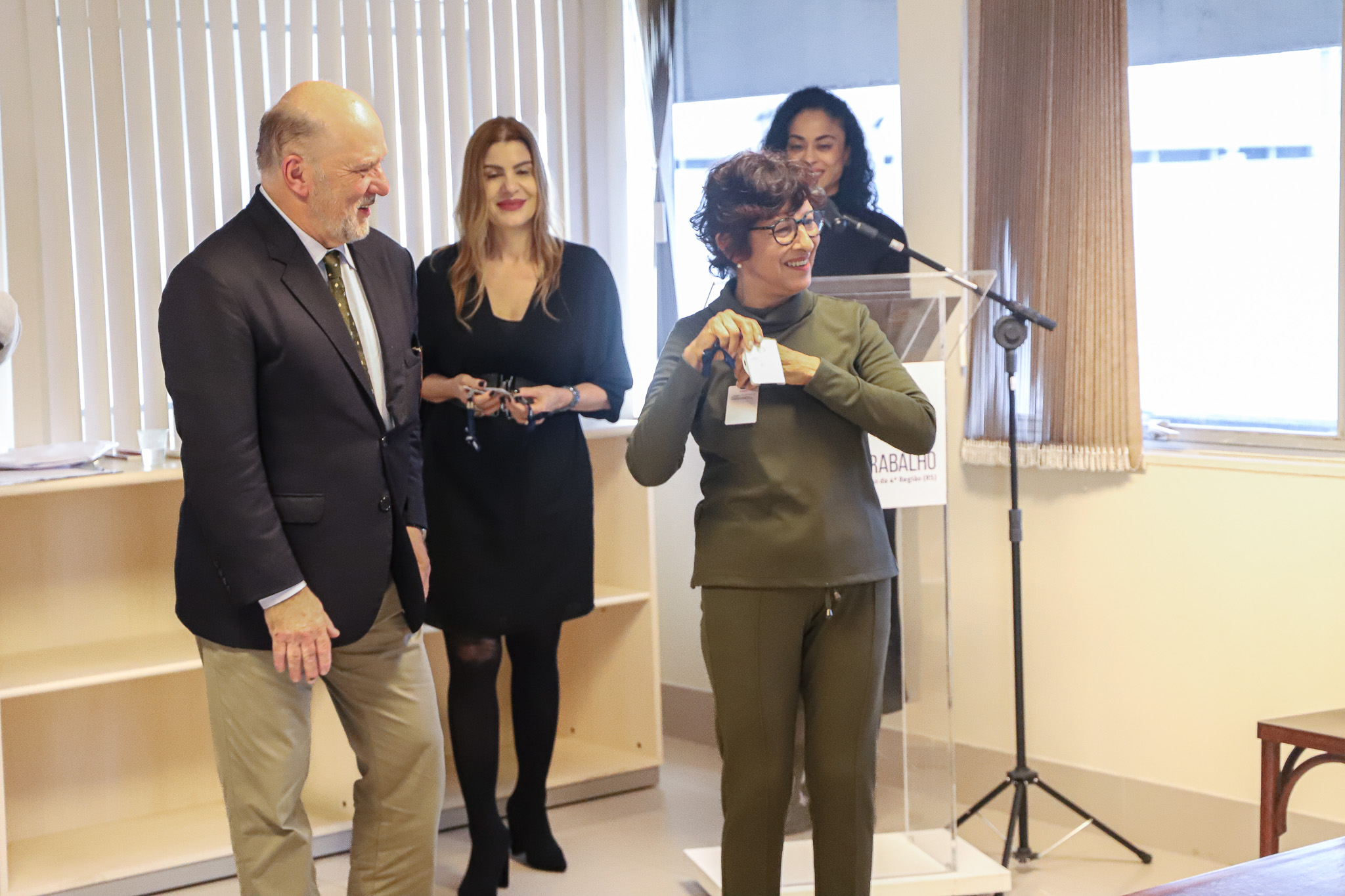 Aposentada recebe crachá simbólico do presidente Ricardo Martins Costa.
