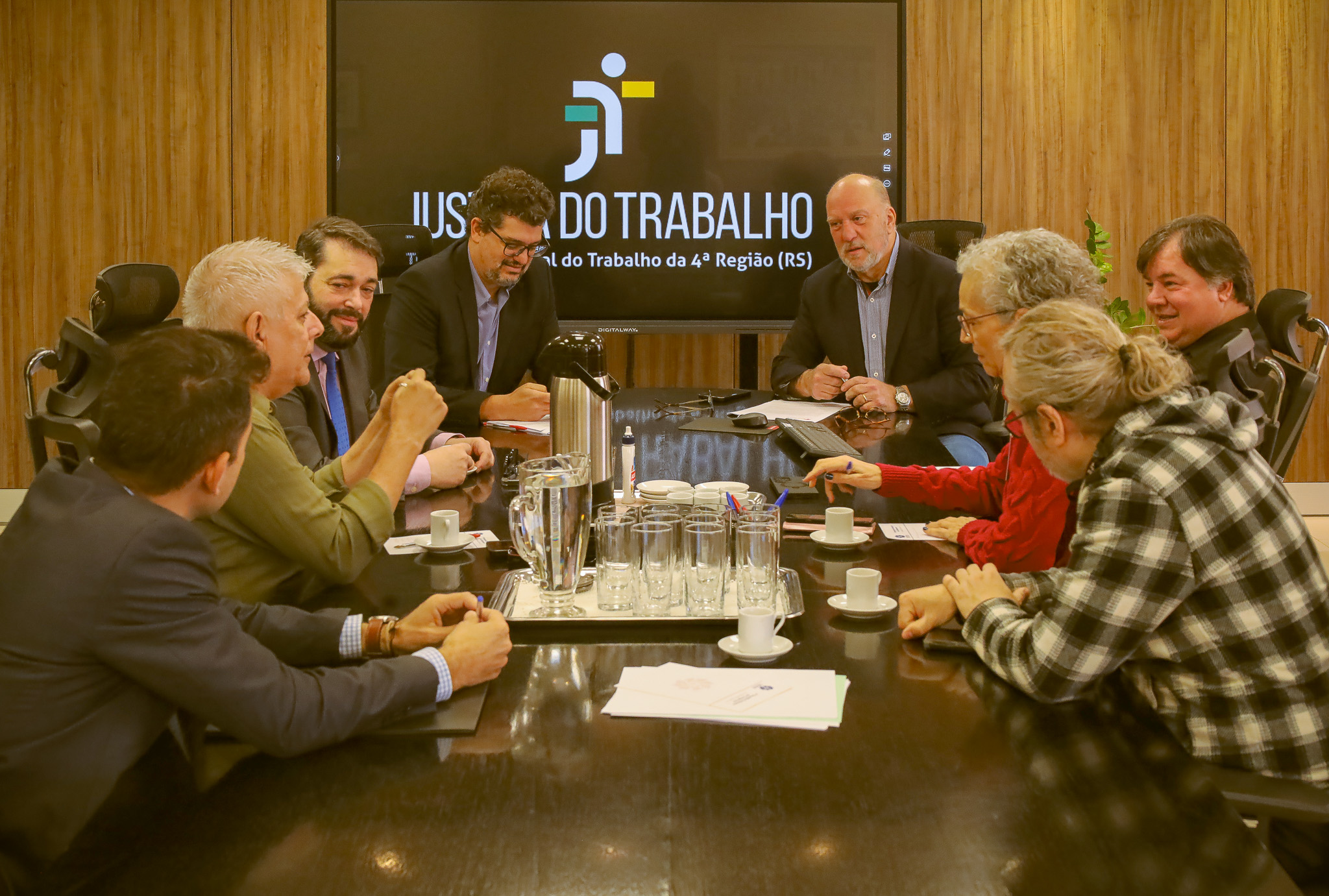 Foto da reunião, mostrando os participantes sentados à mesa do Salão Nobre, conversando.