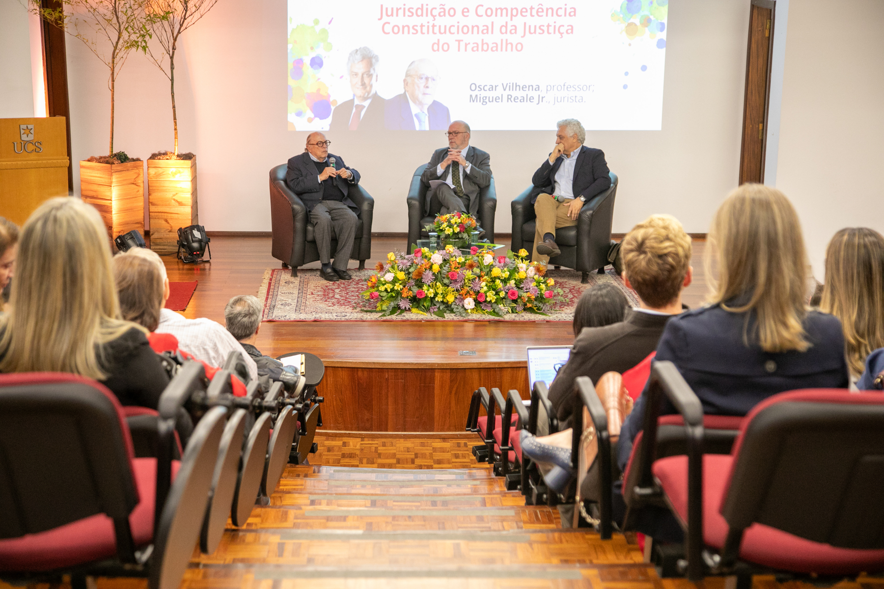 Foto em ângulo aberto, mostrando público em primeiro plano e o palco.