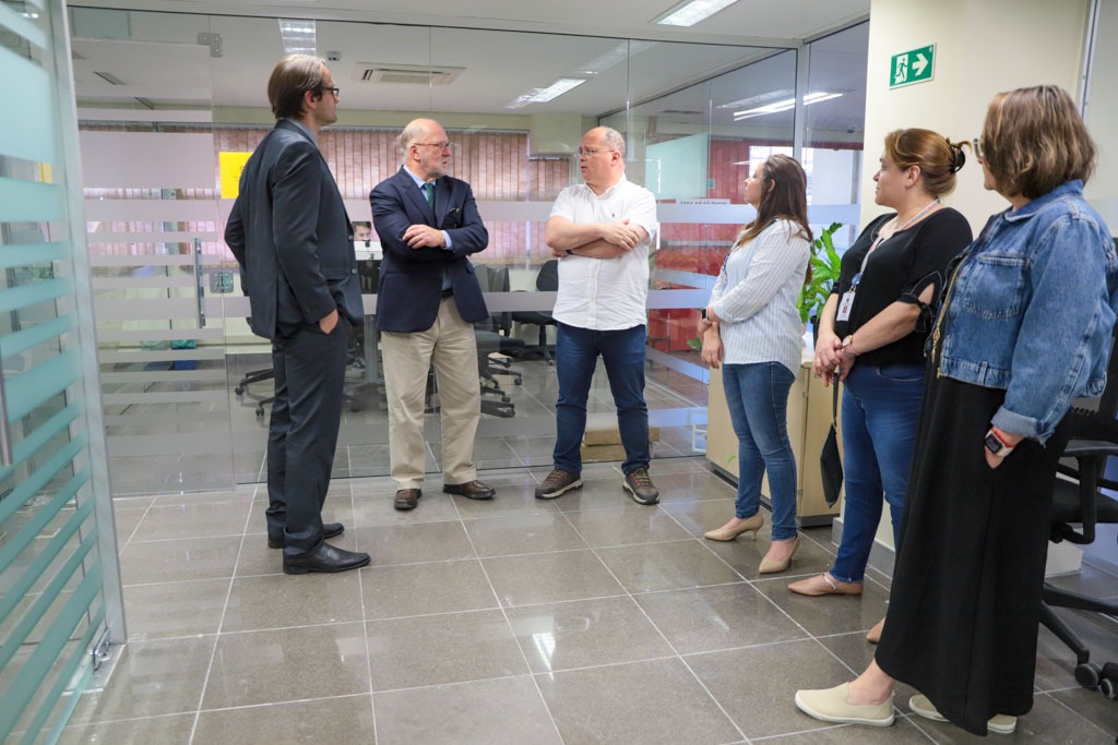 A foto mostra pessoas reunidas conversando de pé.
