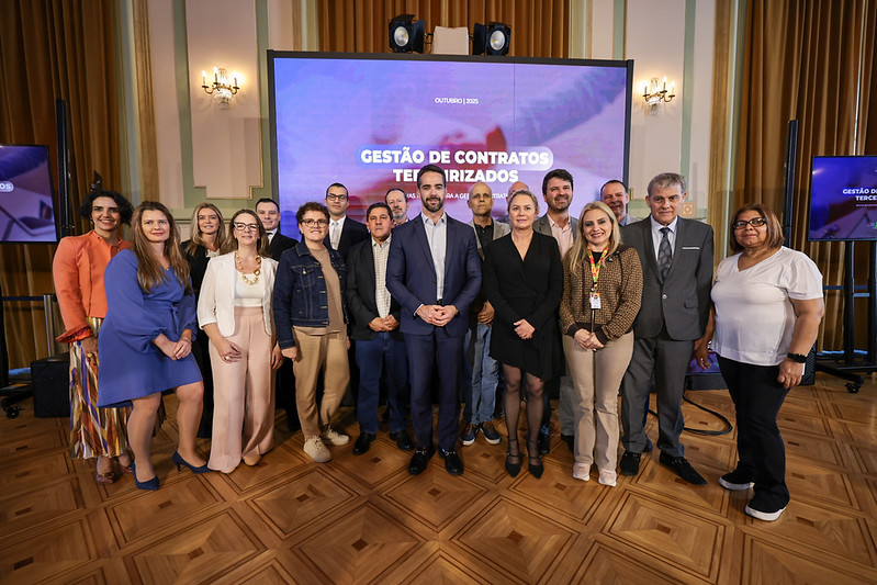 Diversas pessoas posam para a foto. O governador do RS aparece ao centro, e Ricardo Fraga está na direita da imagem.