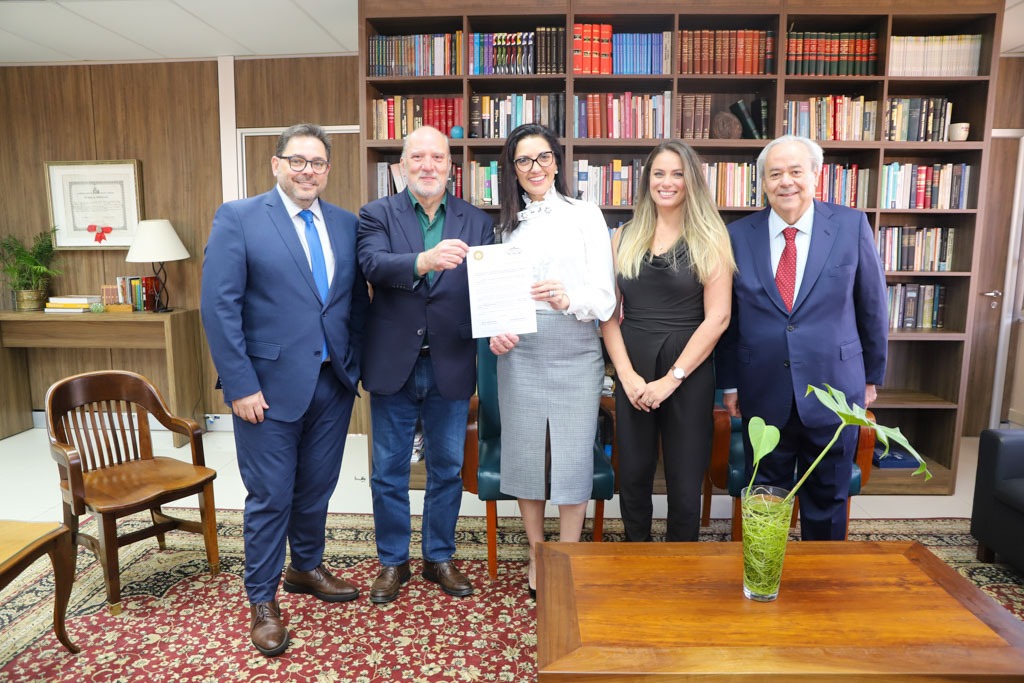 A foto mostra os presentes na reunião com convite em mãos.