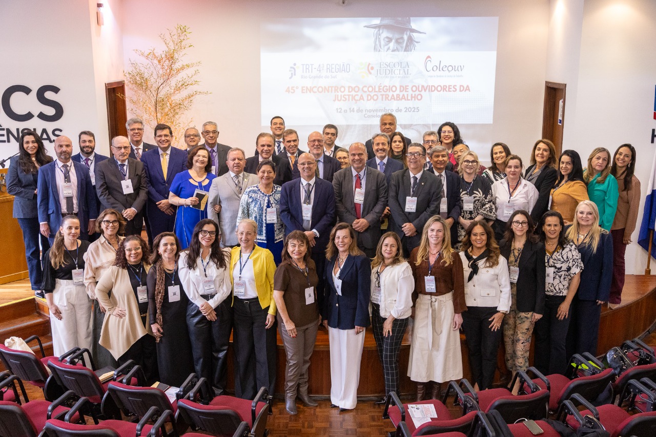 Participantes da reunião posam no auditório sorrindo.
