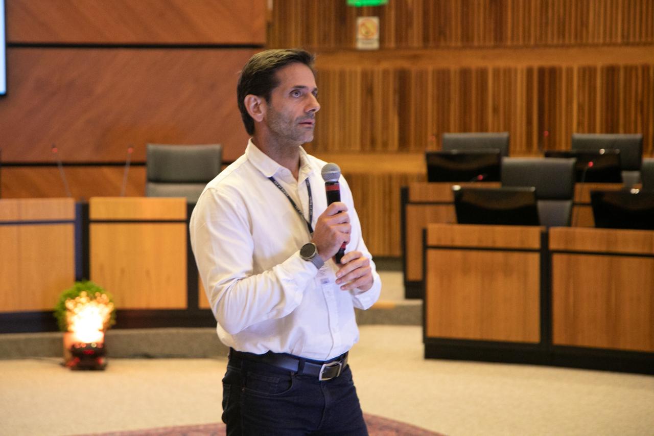 A foto mostra o servidor ricardo falando ao microfone.