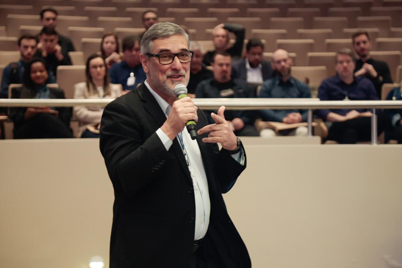 A foto mostra o servidor Peixoto falando ao microfone.