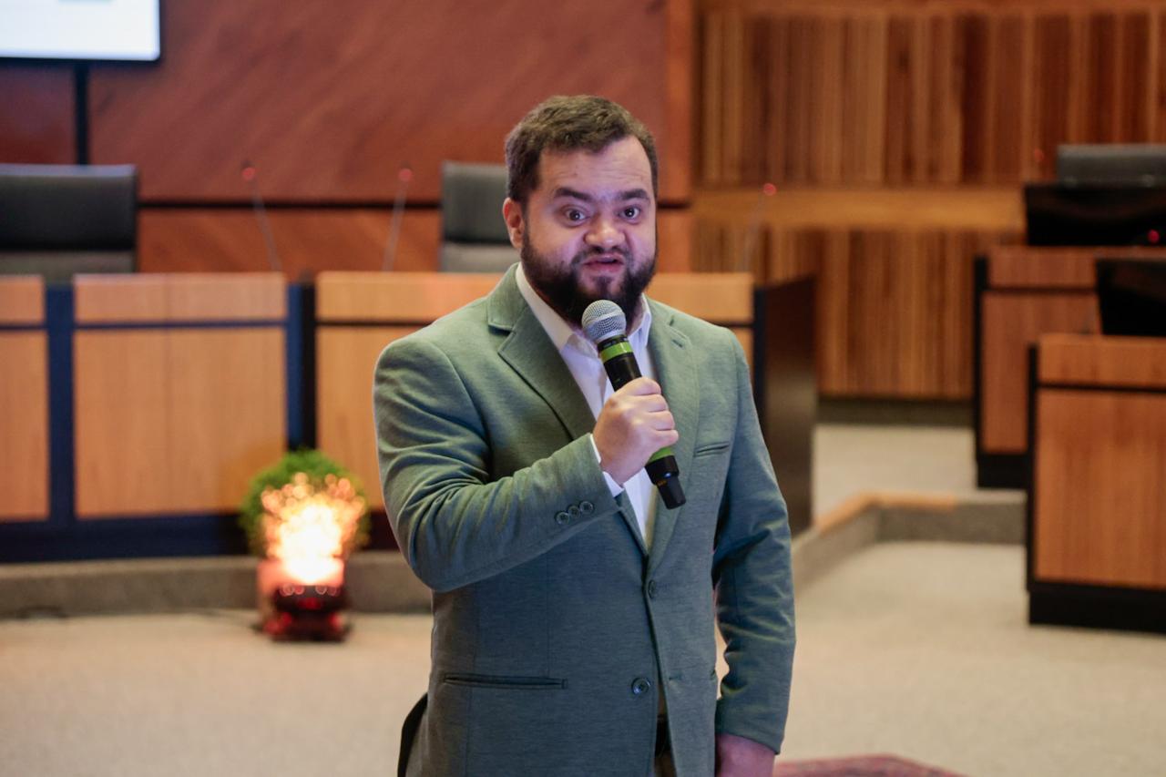 A foto mostra o servidor Juliano falando ao microfone.