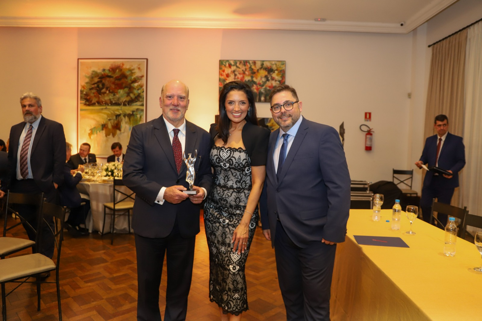 Foto do presidente recebendo prêmio ao lado de duas pessoas