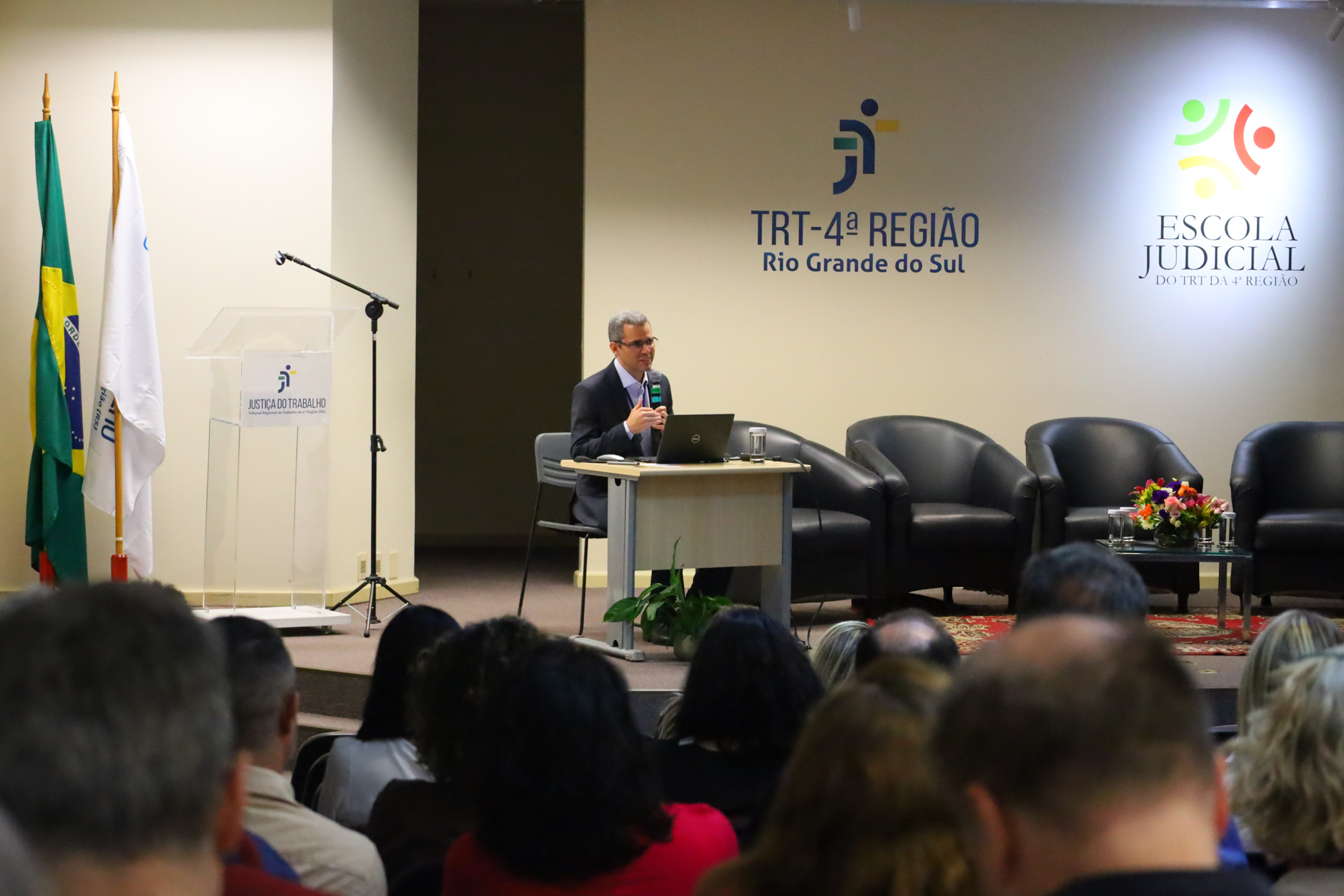 Frederico Cardoso, falando no palco. Público aparece em primeiro plano, de costas.