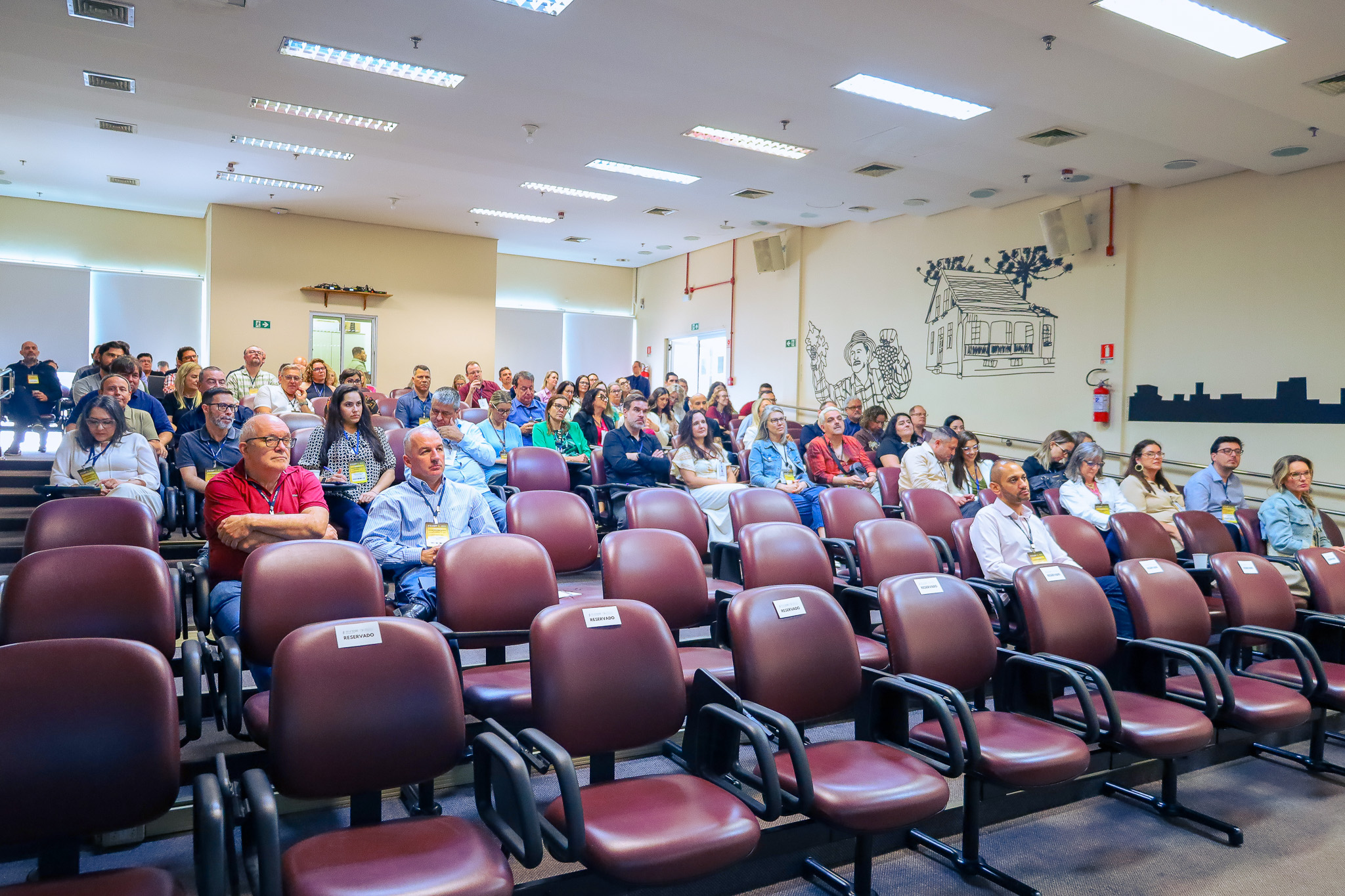 Foto am angulo aberto, mostrando todos os participantes sentados, de frente.