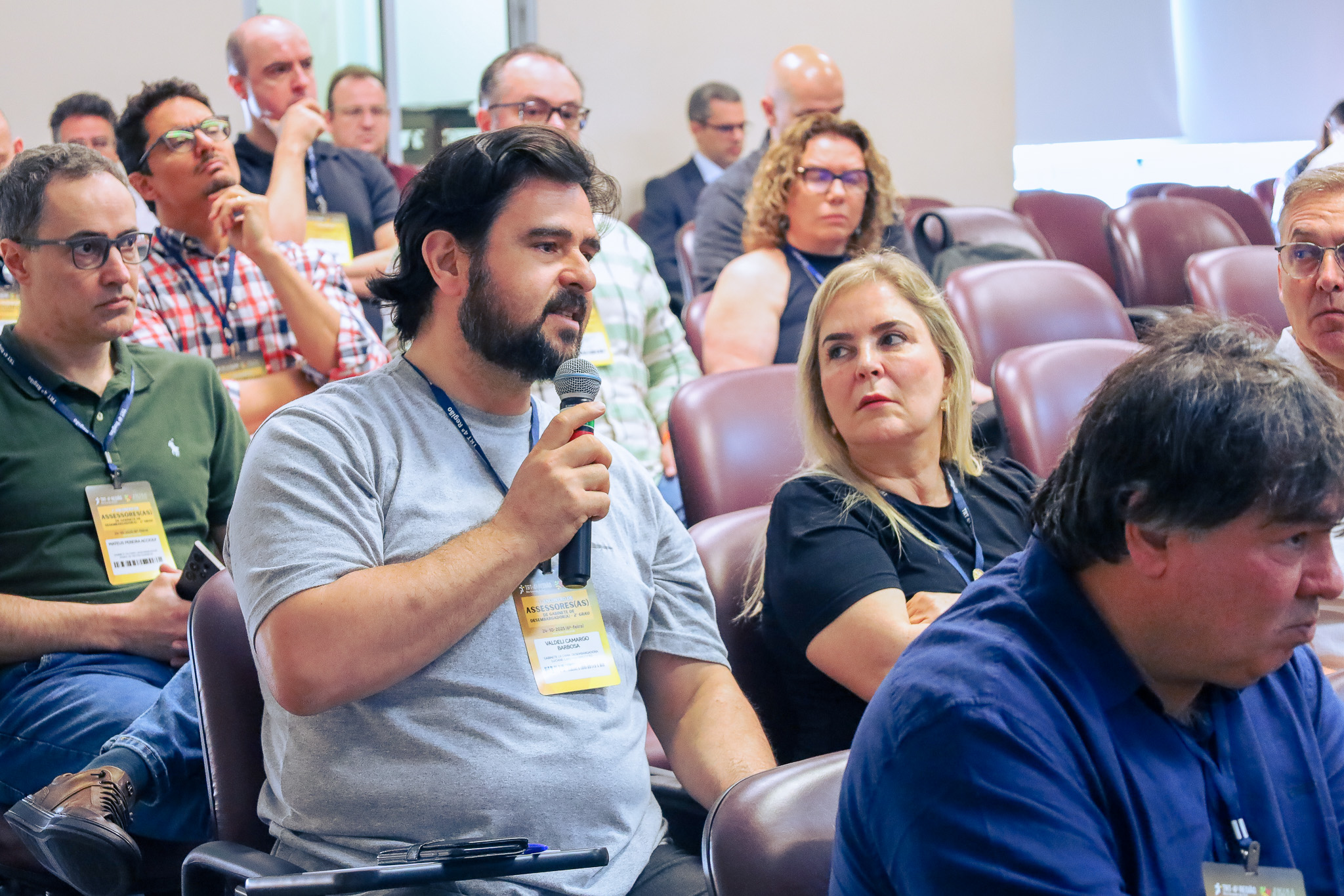 Servidor fala ao microfone, na plateia.