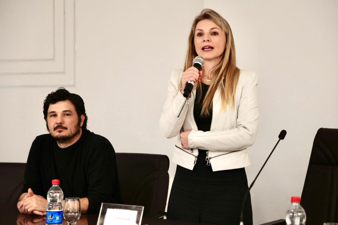 A foto mostra luciele em primeiro plano palestrando. 