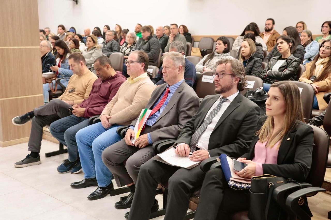 A foto mostra público com painelistas.