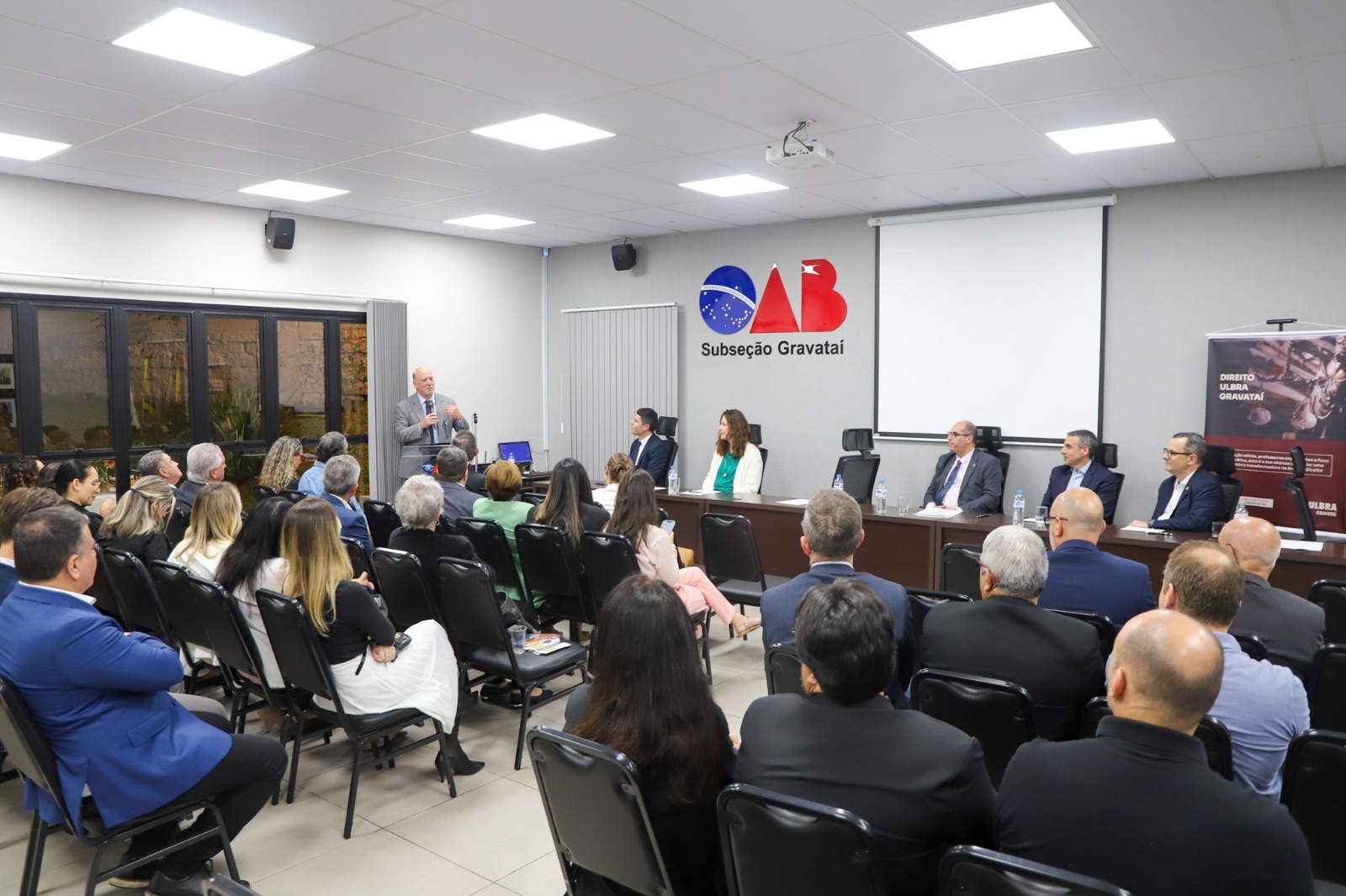 A foto Martins Costa mais de fundo com pessoas em frente.