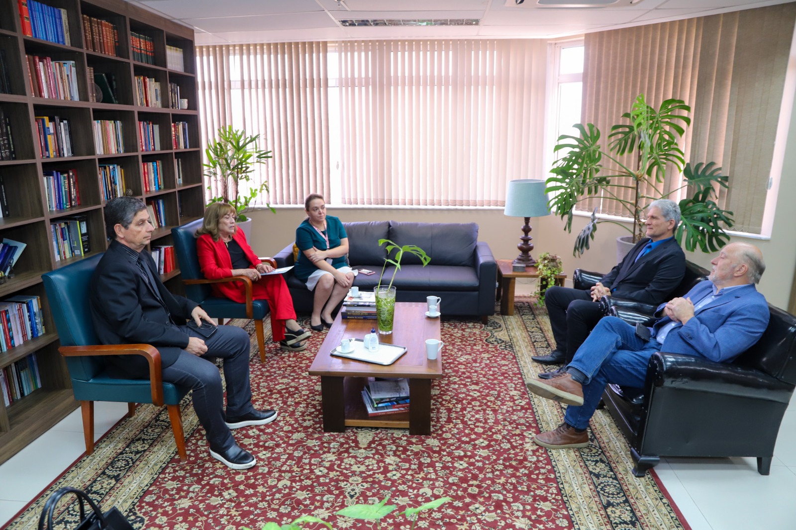 A foto mostra cinco pessoas sentadas em poltronas.