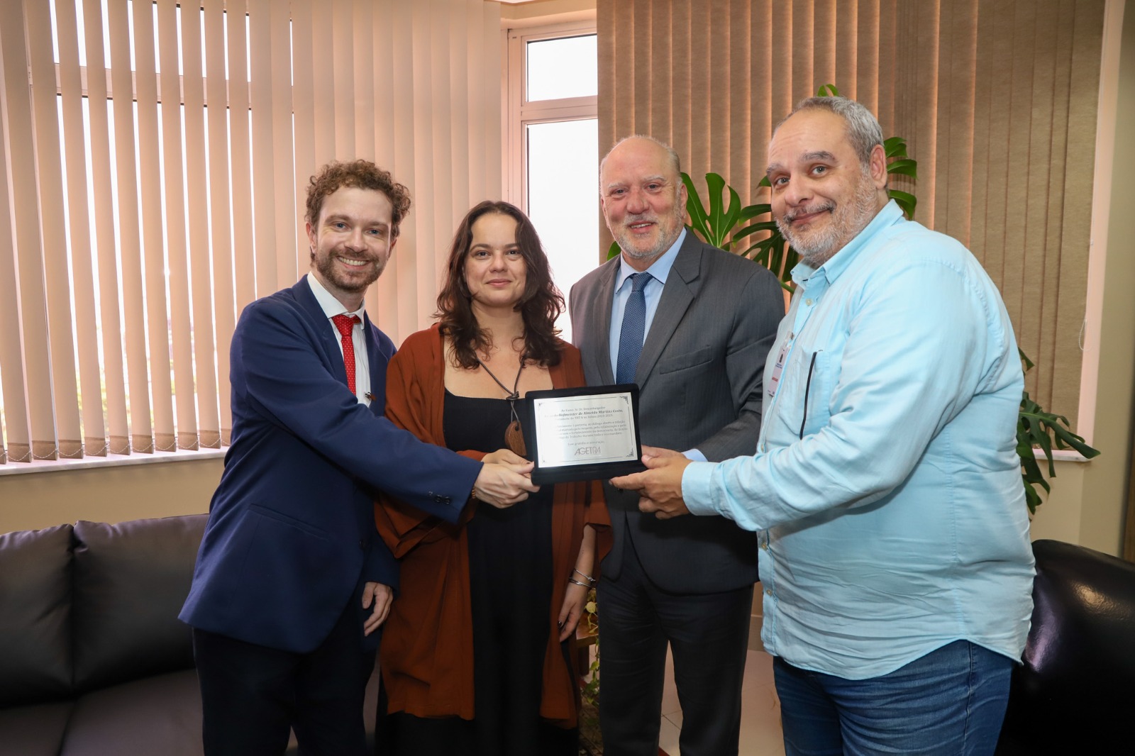 A foto mostra quatro pessoas segurando uma placa.