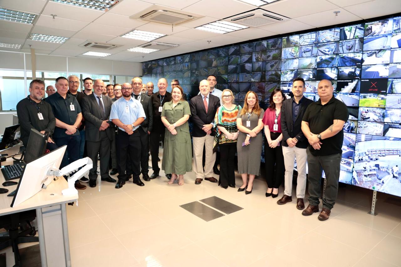 A foto mostra pessoas posando para foto na sala de segurança.