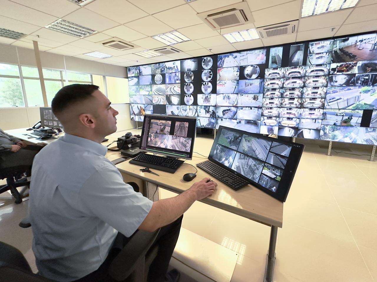 Foto de um vigilante analisando imagens e as telas de fundo.