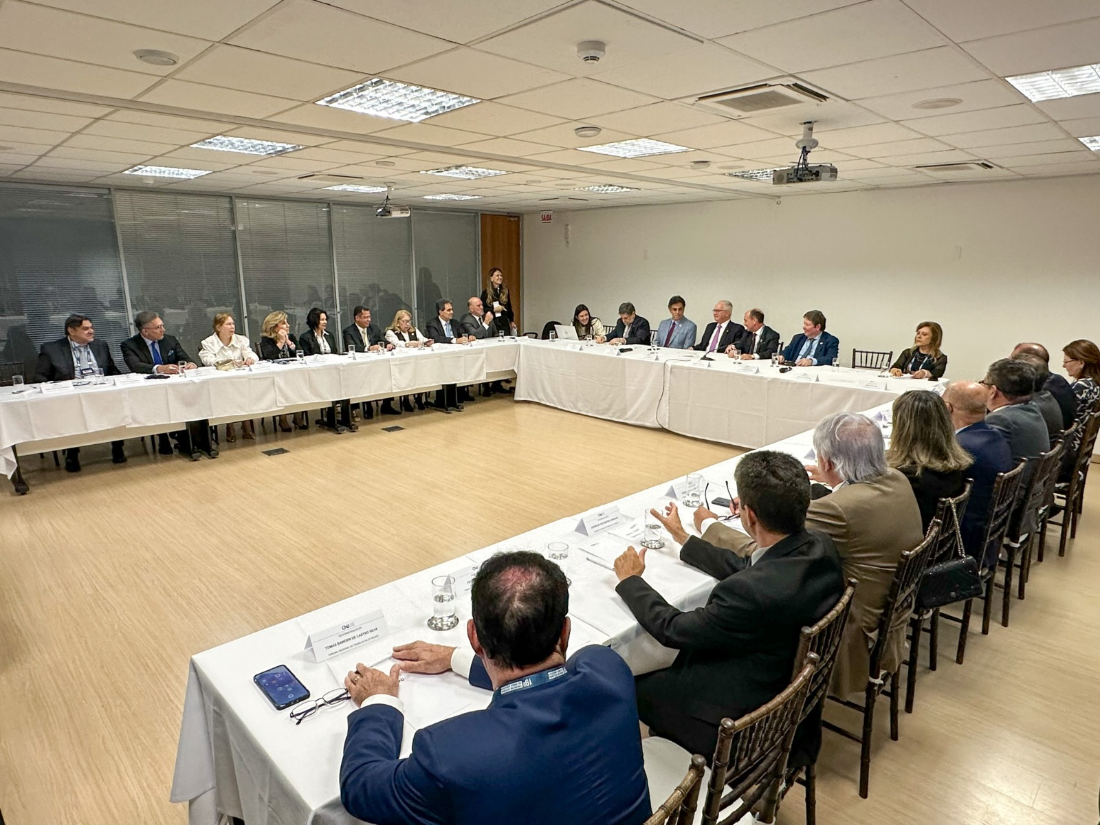 A foto mostra presentes em reunião em mesas.