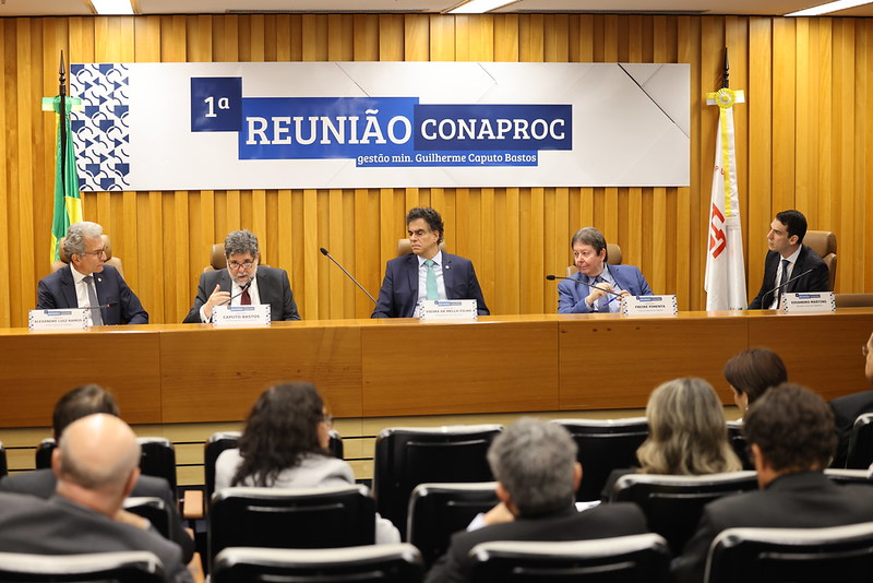 A foto mostra ministros numa mesa de autoridades de um auditório.