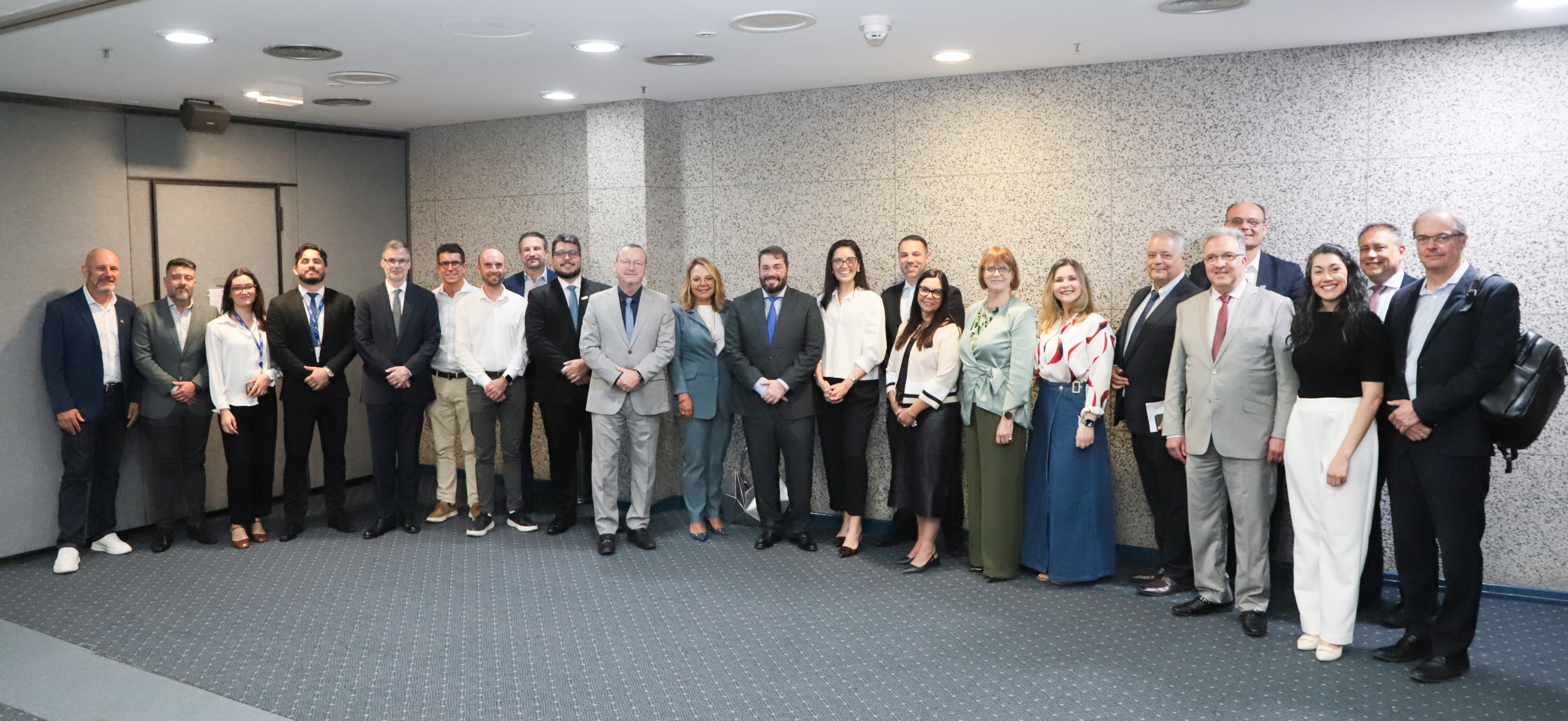 Diversas pessoas posam para a foto de pé sorrindo. 