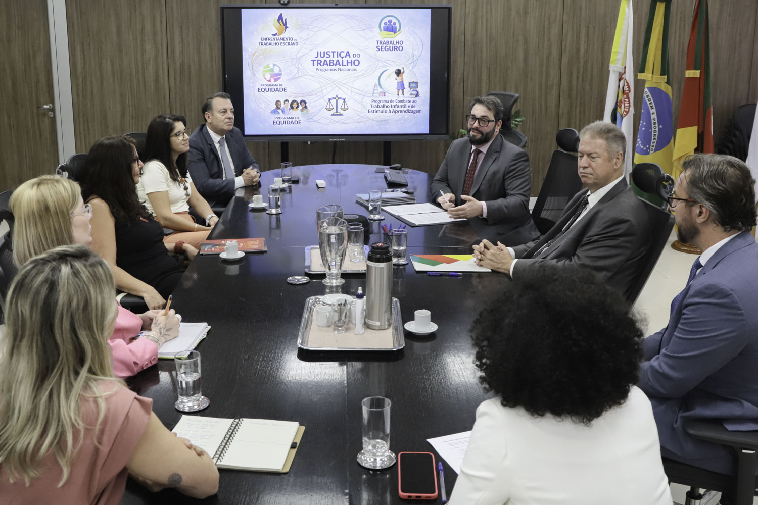 Foto da reunião, mostrando os participantes sentados à mesa do Salão Nobre, conversando