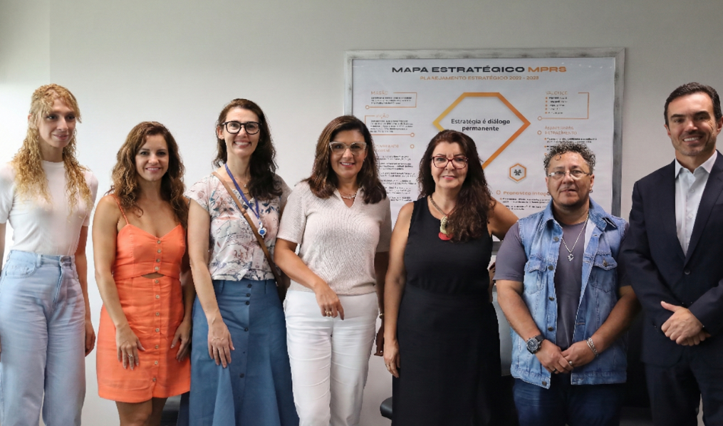 Sete integrantes do grupo posam para a fotografia alinhados à frente de um painel do Mapa Estratégico do MPRS, que traz em destaque a frase "Estratégia é diálogo permanente".