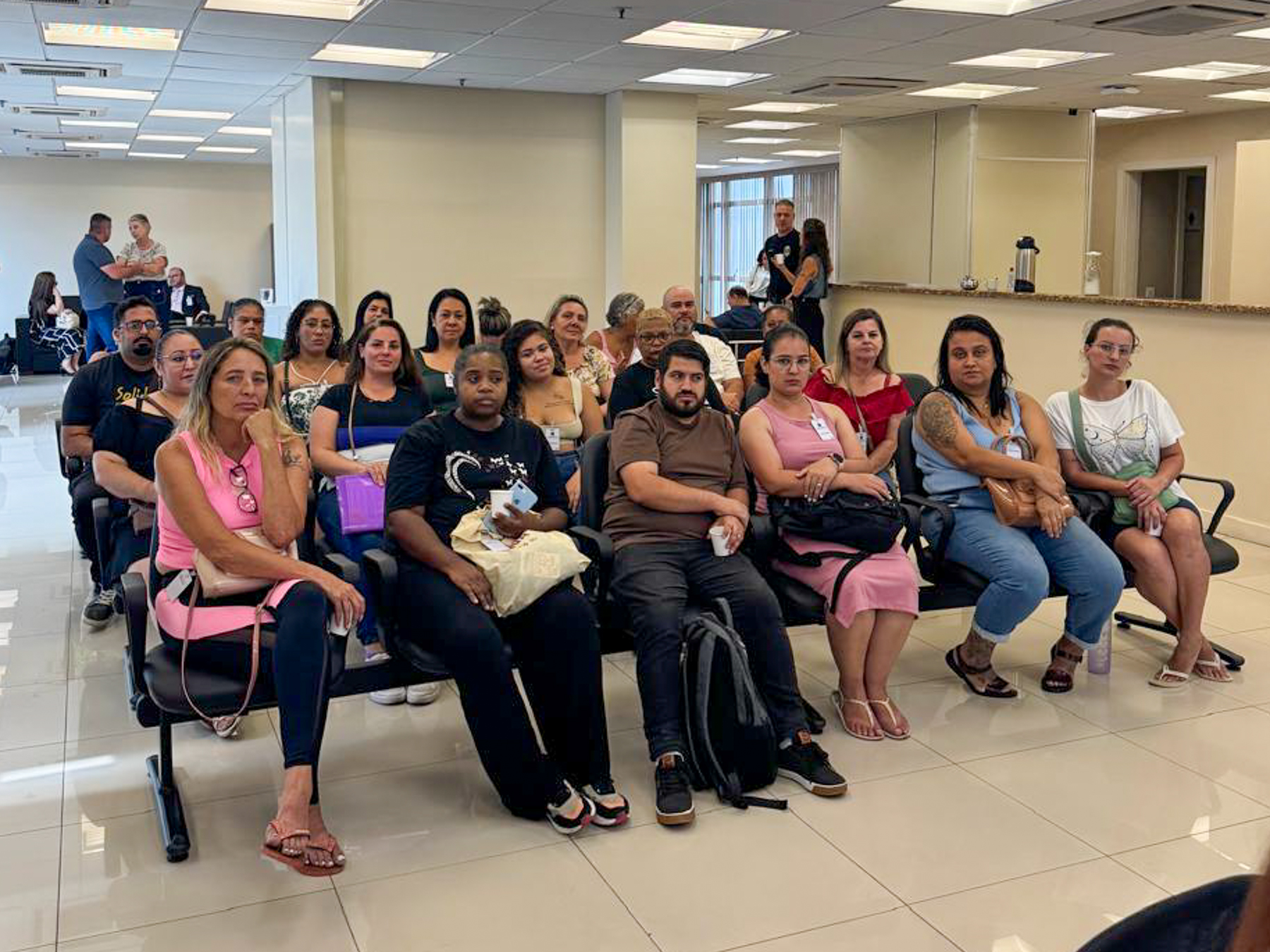 Trabalhadores, sentados, assistindo à audiência