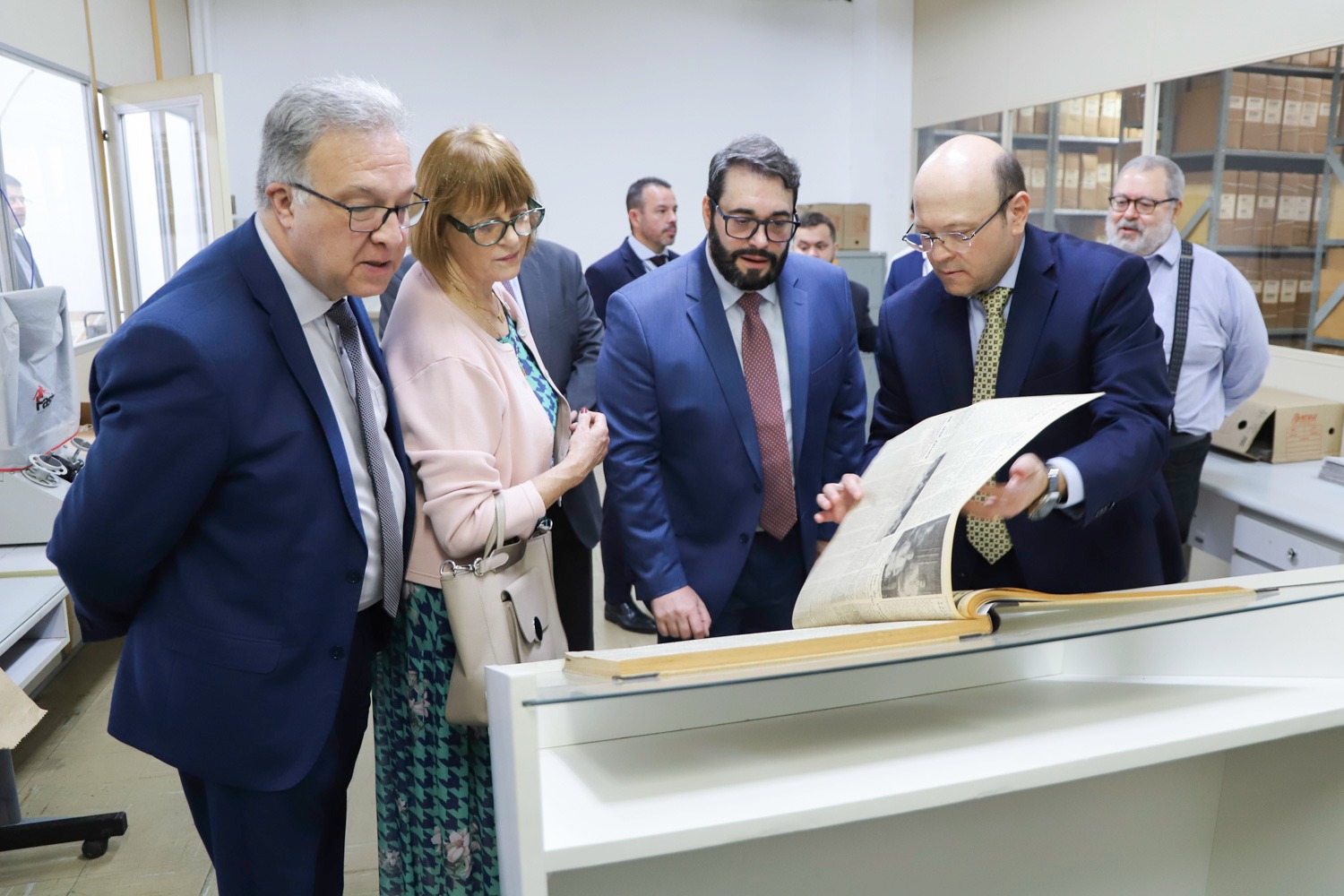 A foto mostra quatro pessoas olhando um jornal.