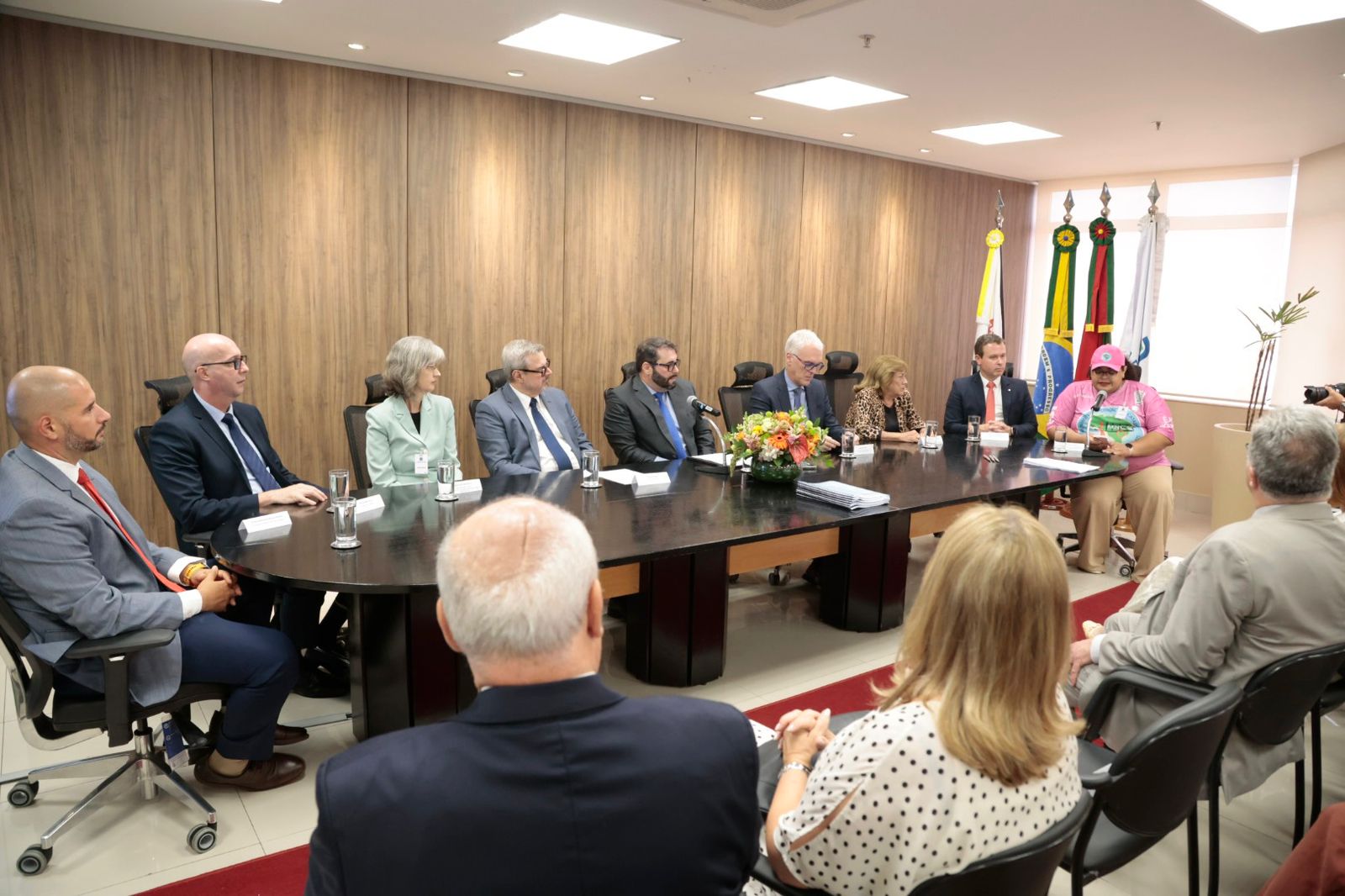 Mesa oficial do evento. No canto direito, a representante dos trabalhadores está falando ao microfone.