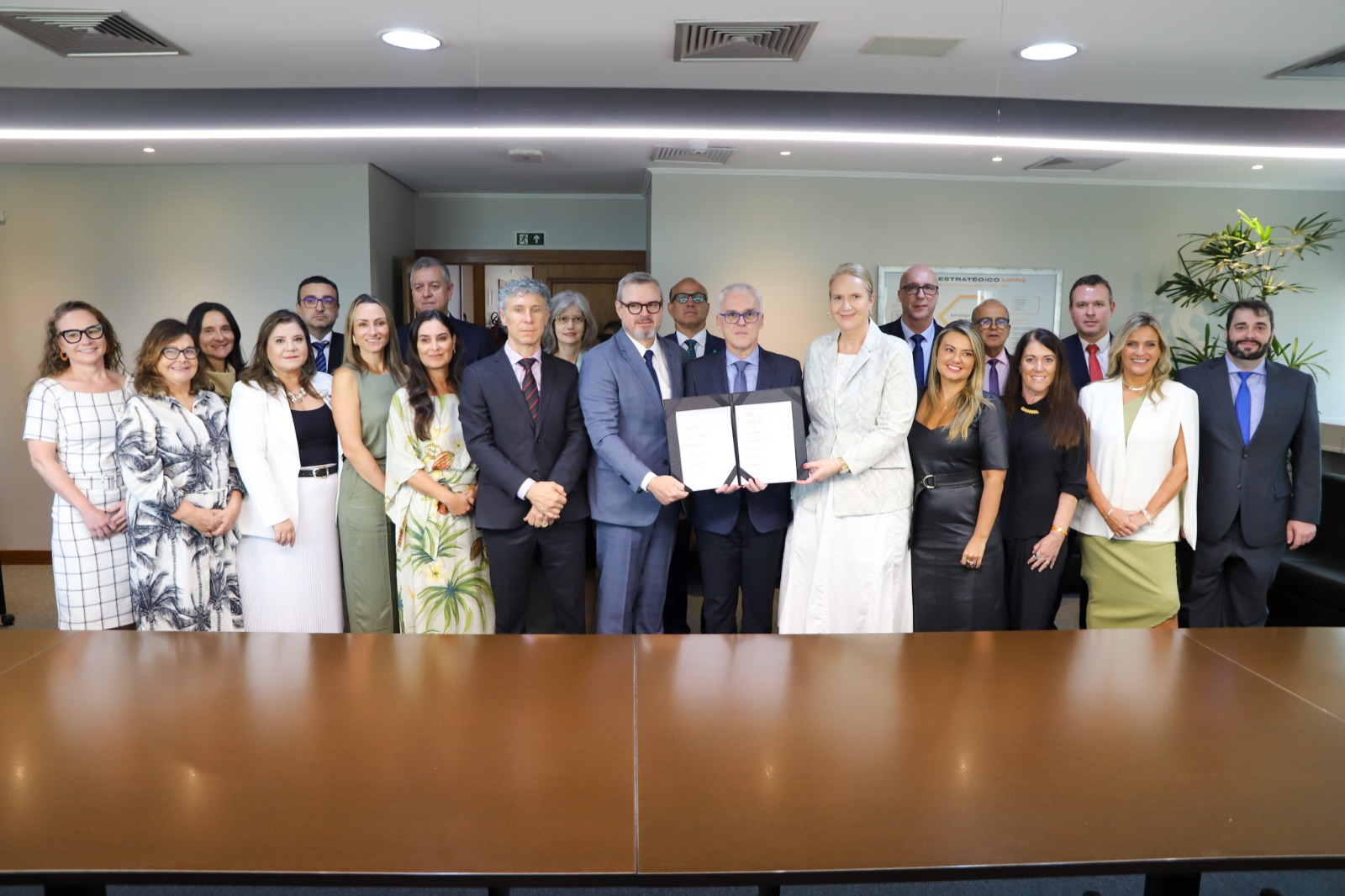 A foto mostra várias autoridades posando para foto com termo de cooperação sendo mostrado.