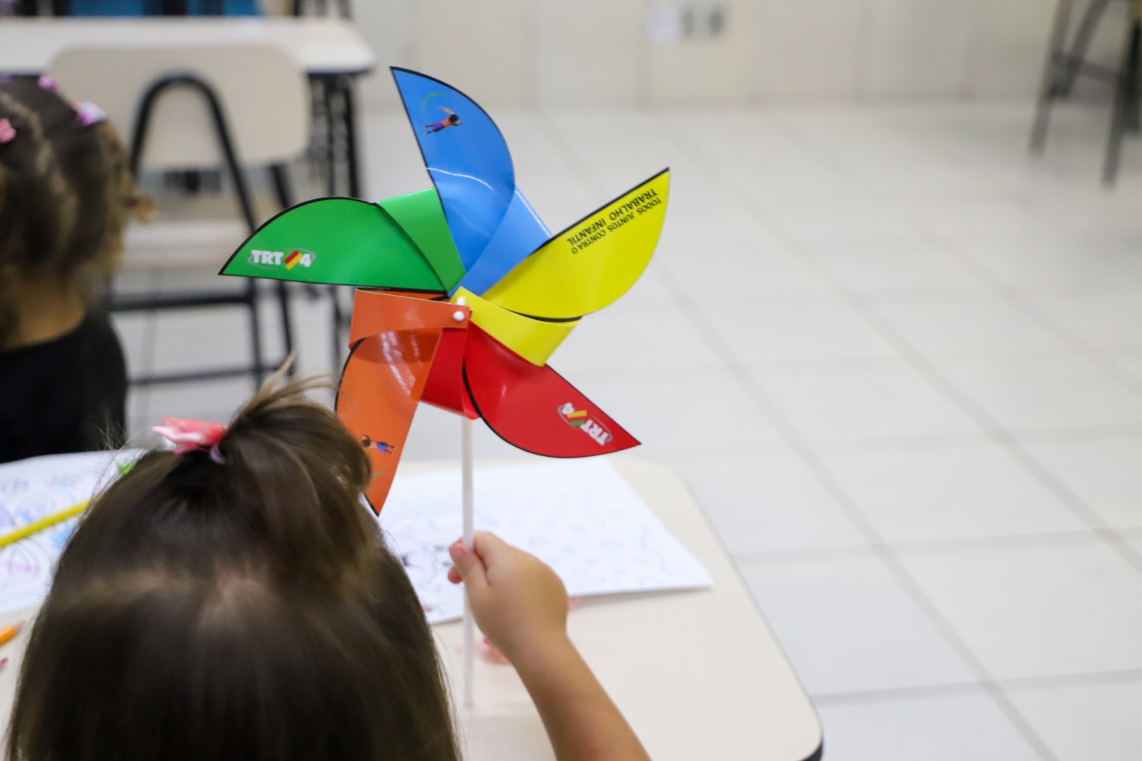 A foto mostra uma criança de costas com catavento.