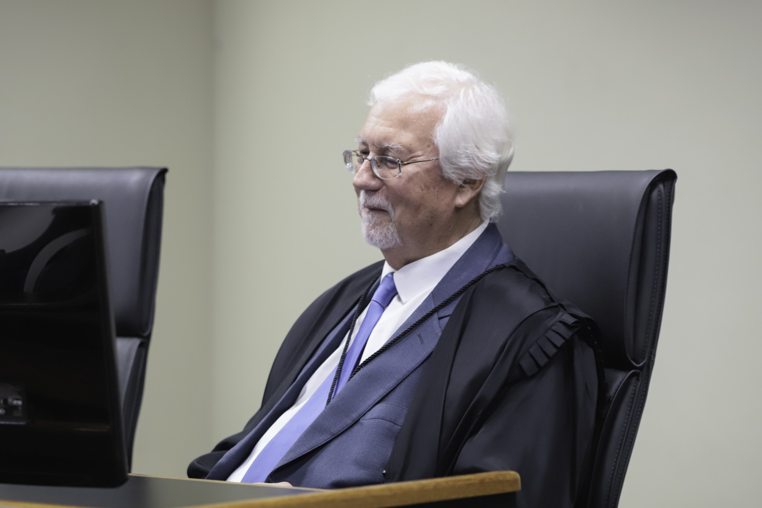 João Aflredo branco e grisalho. Usa óculos de grau fino e vesta toga. Está sorrindo.