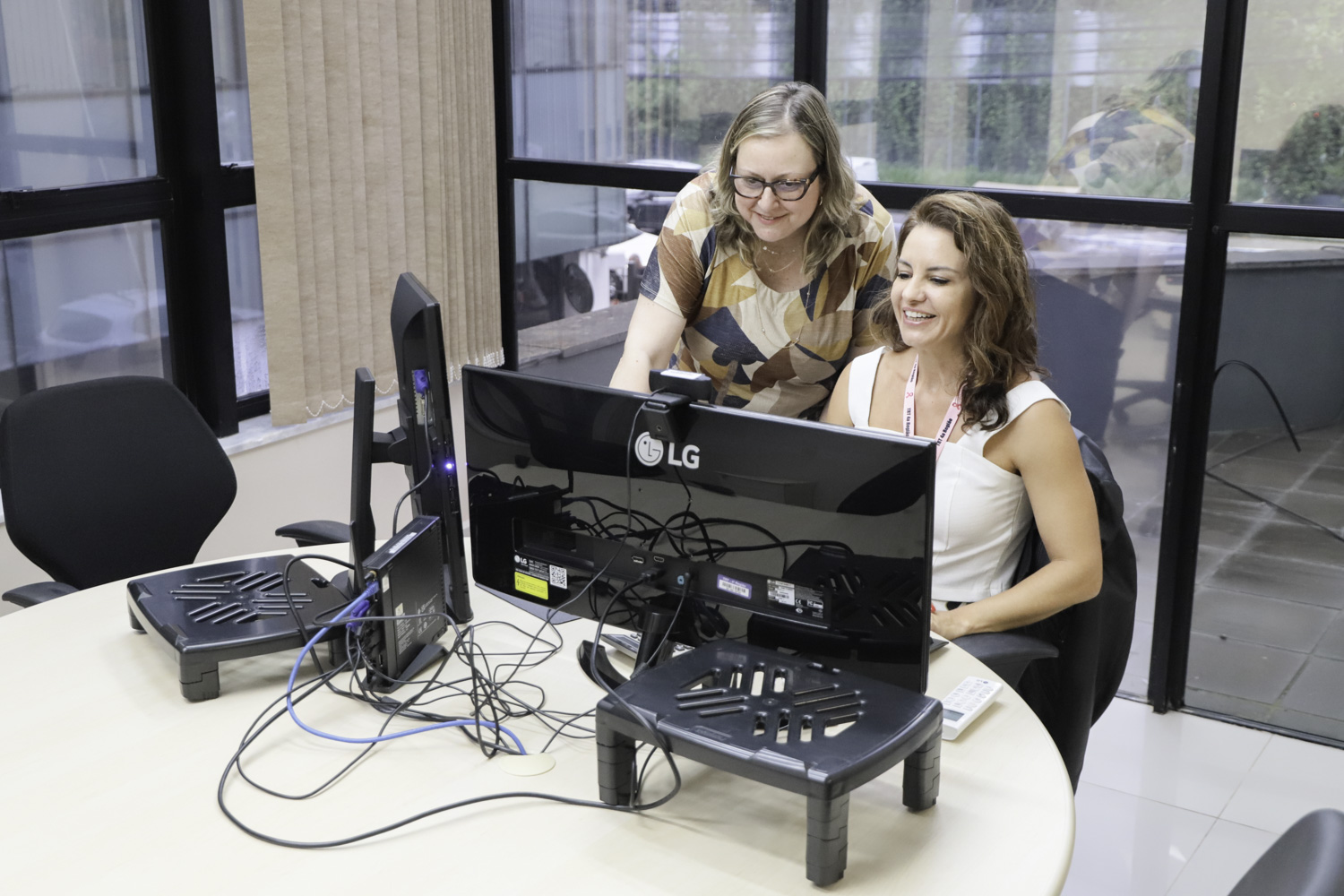 Duas mulheres estão sorrindo e olhando para a tela de um computador.