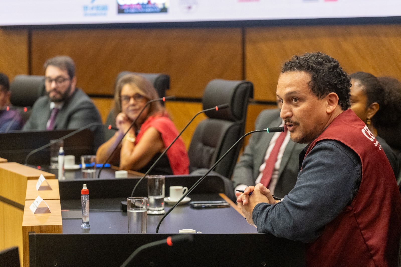 Julio é negro, tem cabelo cacheado preto e fala ao microfone