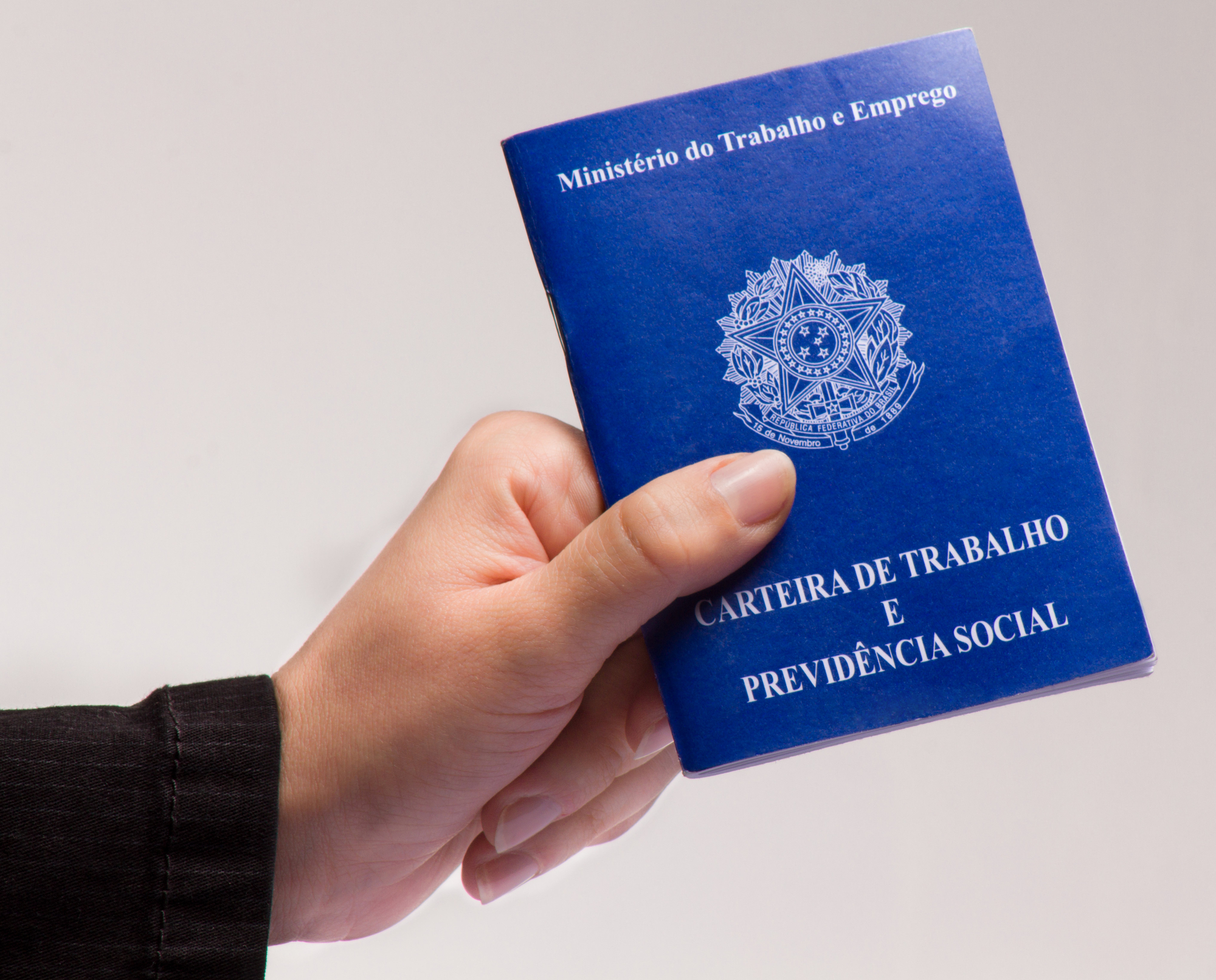 mão segurando uma carteira de trabalho