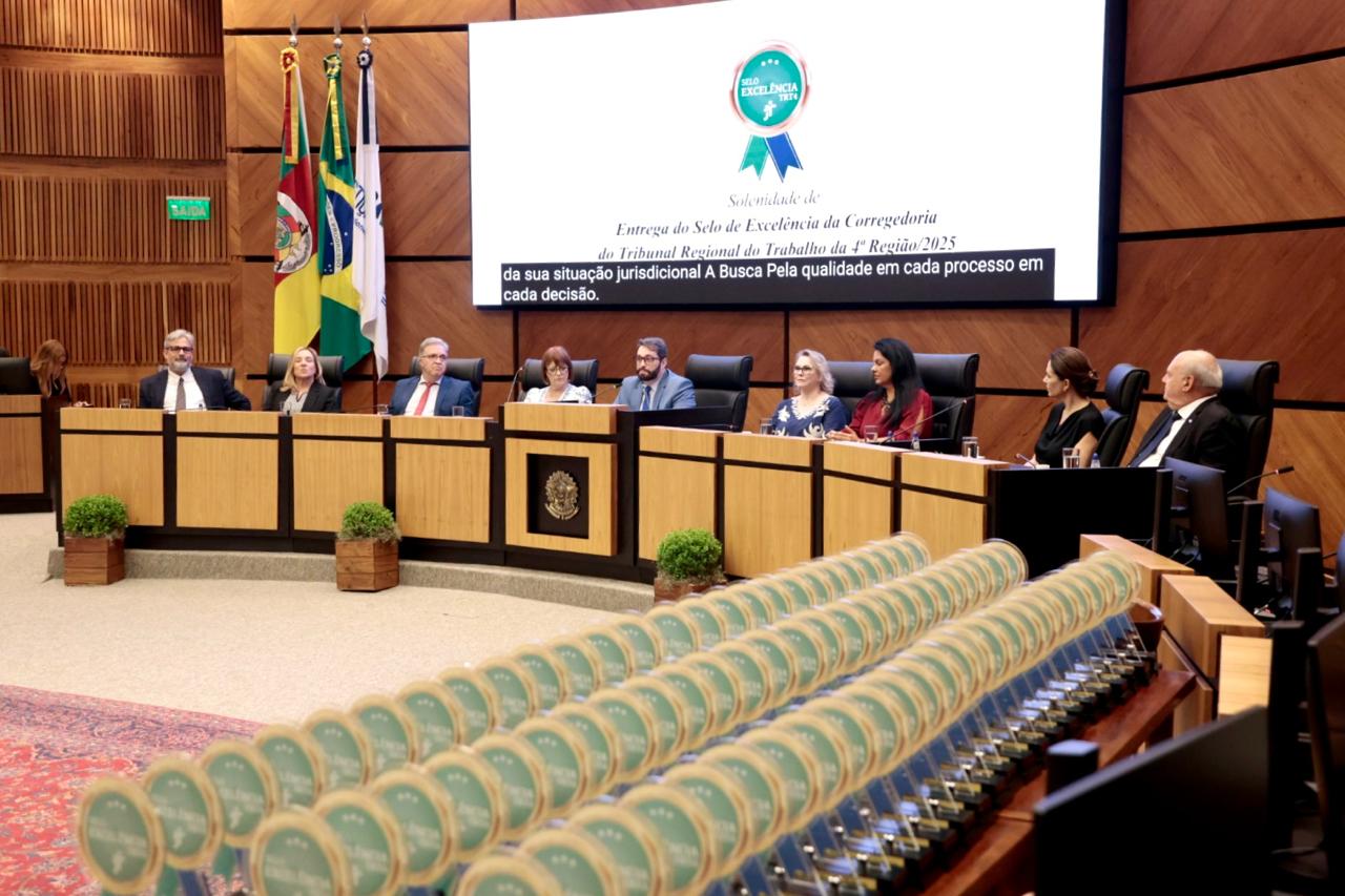 Mesa oficial ao fundo e troféus alinhados em primeiro plano. 