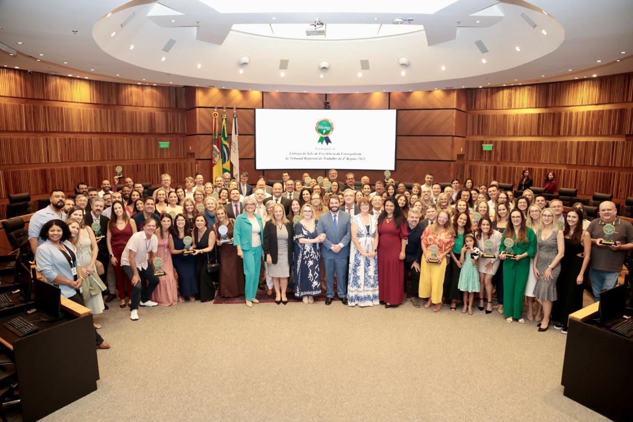 diversas pessoas posam para a foto na nave do plenário, alguns seguram o trofeu da premiação.