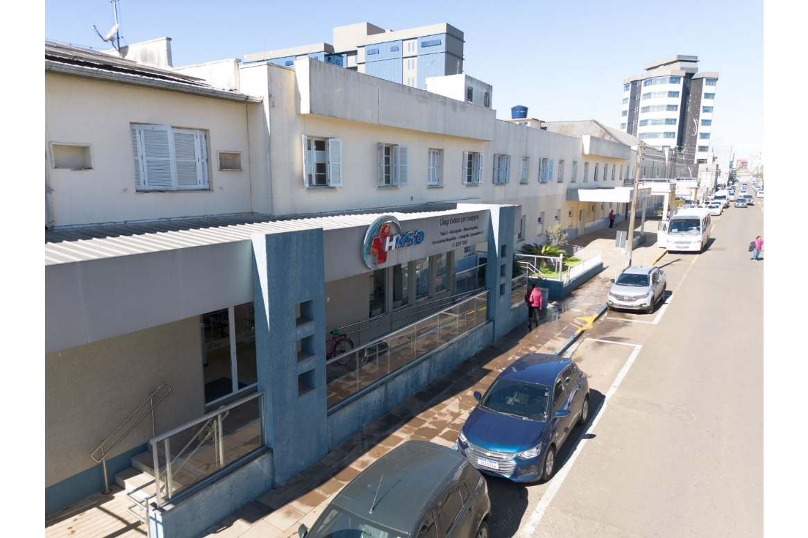 Fachada do hospital com carros estacionados na rua à frente