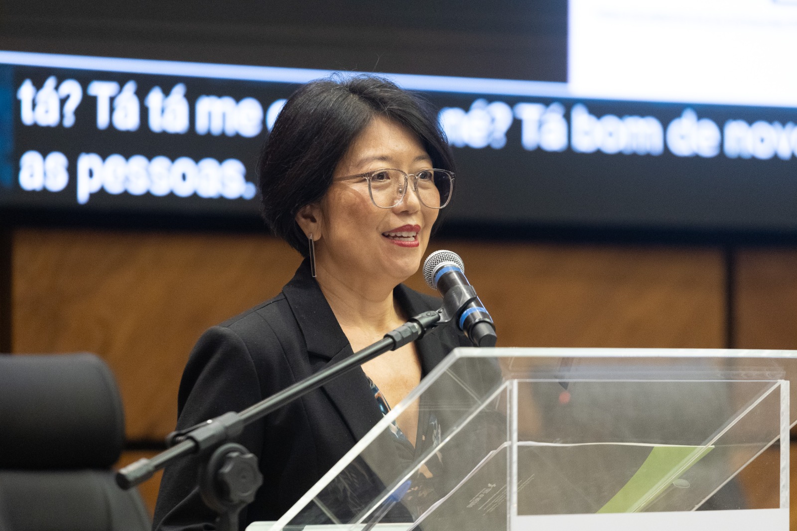 Patrícia é amarela. tem cabelo preto e liso. Usa óculos. 