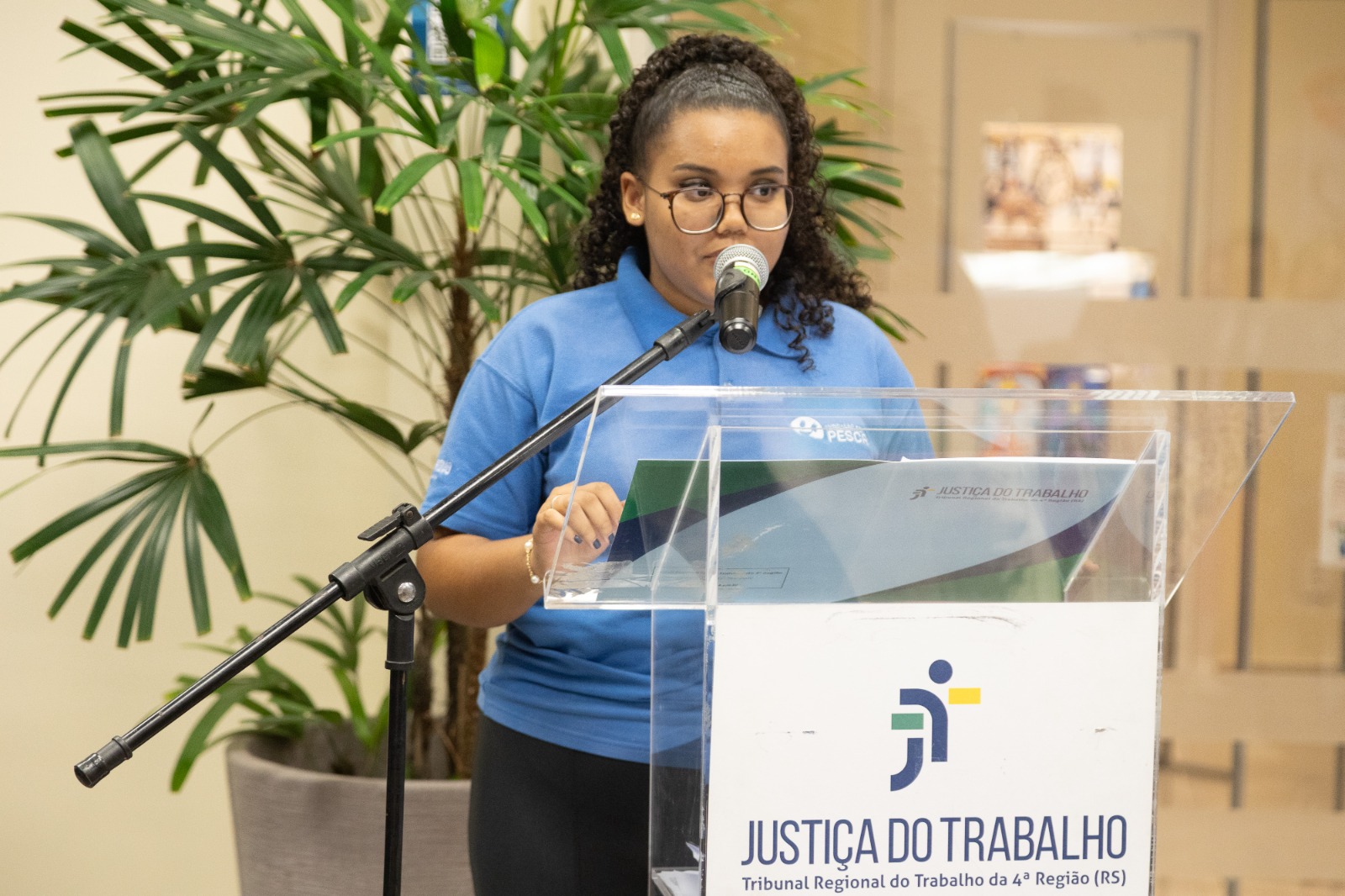 Thayssa é negra e tem cabelo comprido. Usa uniforme do Pescar e fala no púlpito