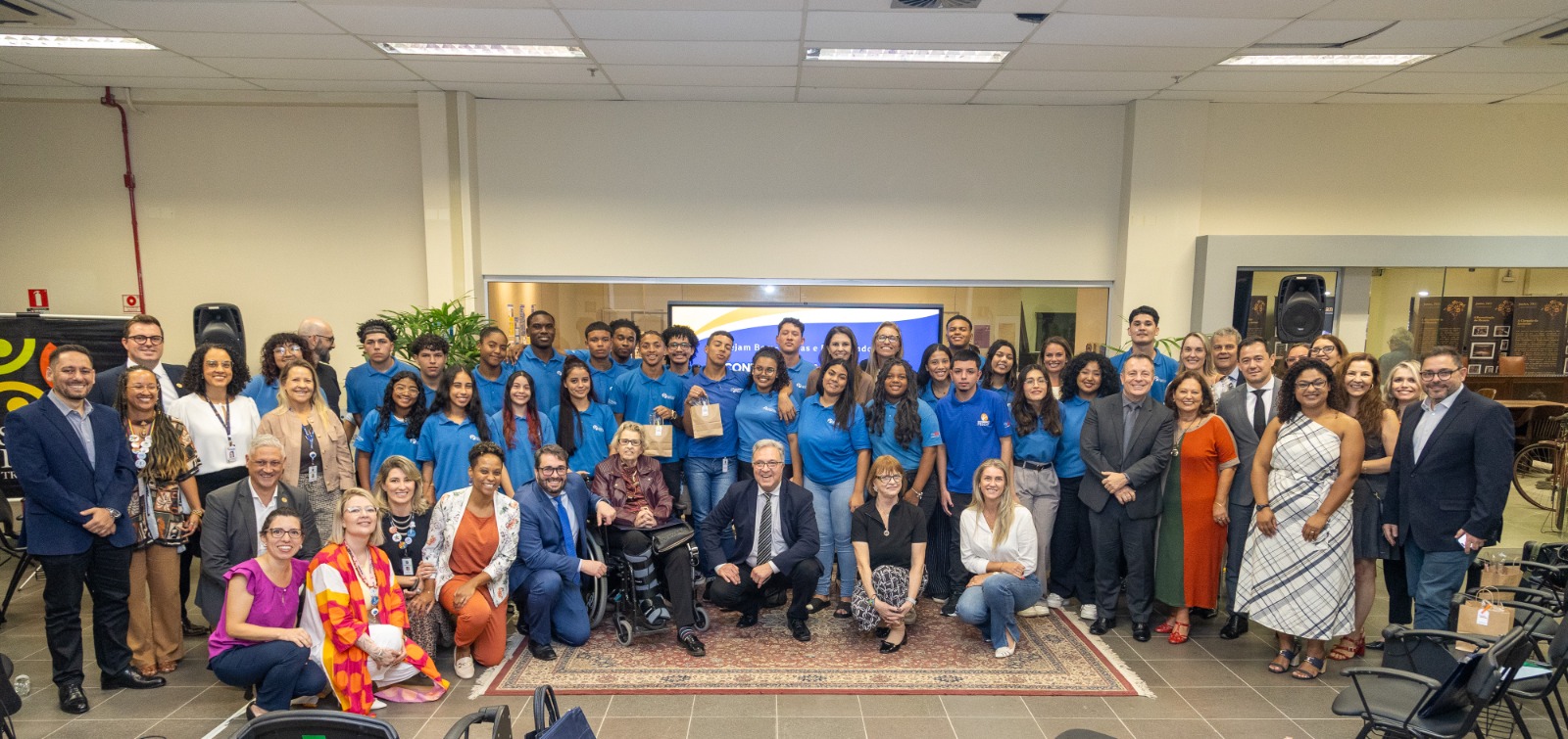 participantes posam para a foto sorrindo, alguns de pé e outros abaixados na primeira fila. 