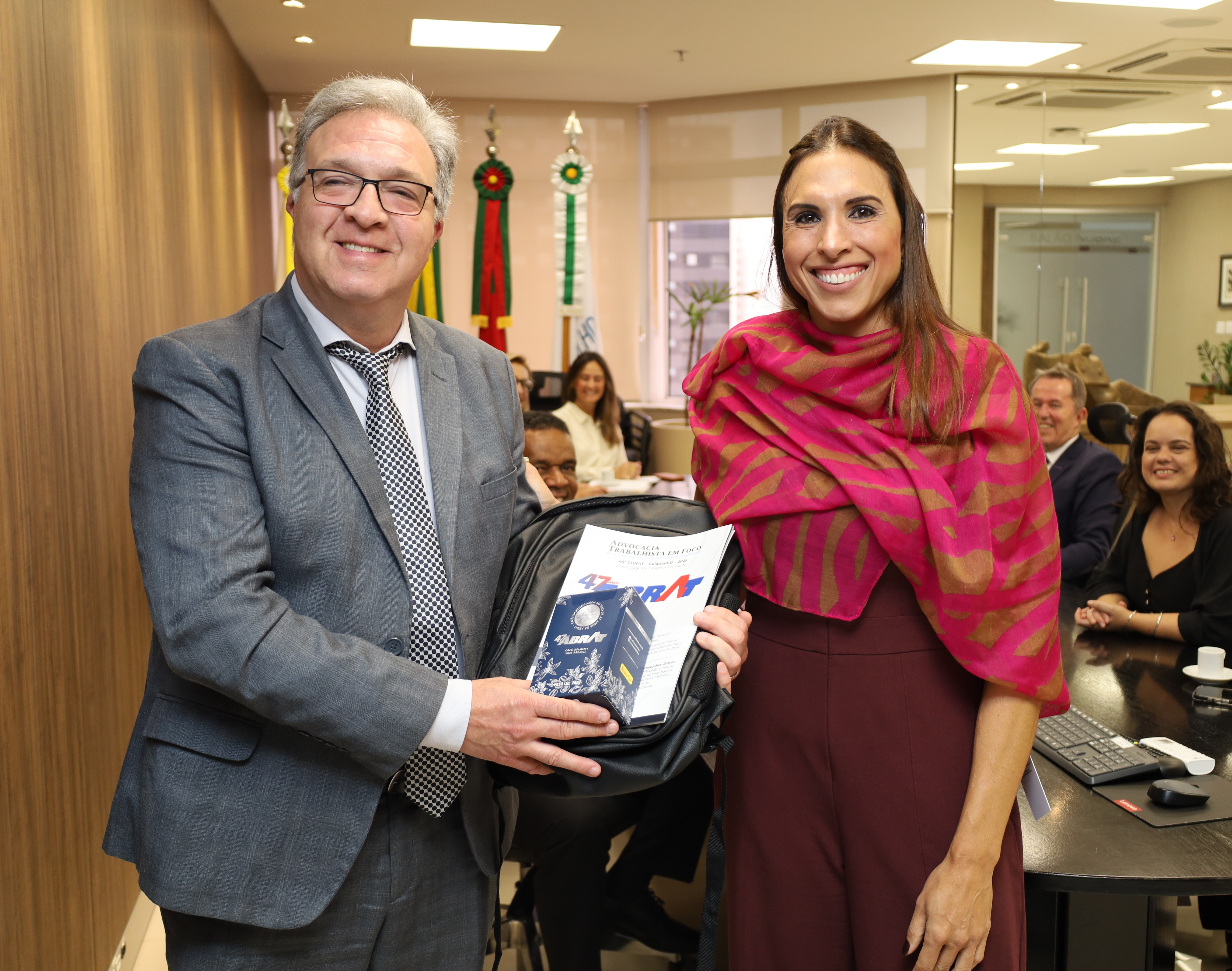 A fotografia mostra o desembargador Cláudio Antônio Cassou Barbosa recebendo presente de cortesia da presidente da Abrat, Elise Correia.