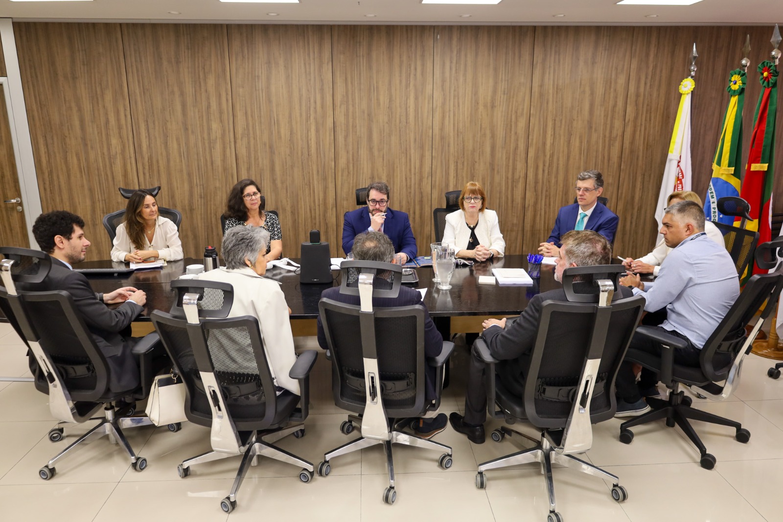 A foto mostra uma reunião ao redor de uma mesa.