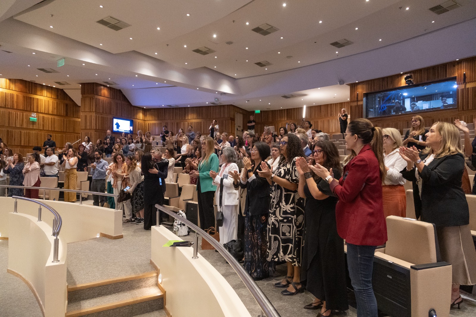 diversas pessoas na plateia estão em pé aplaudindo